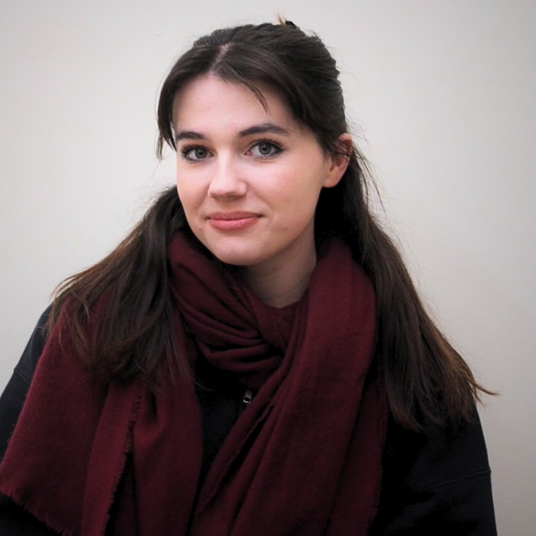 A young woman with dark hair looks toward the camera with a slight smile.
